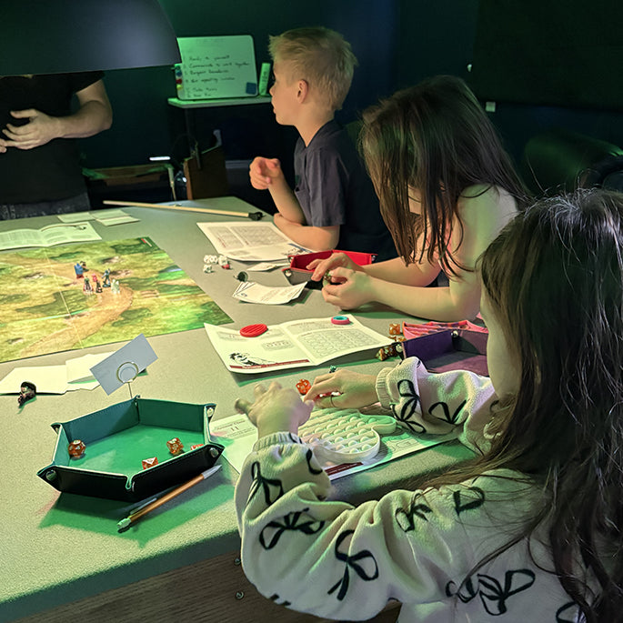 Children playing tabletop roleplaying with game pieces and a map on a table.