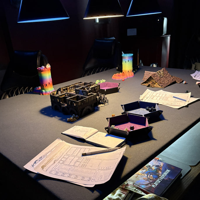 Tabletop gaming setup with models, dice, and game sheets on a dark surface.